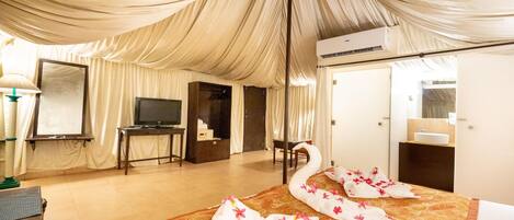A room with a bed, a television, a desk, and a mirror.