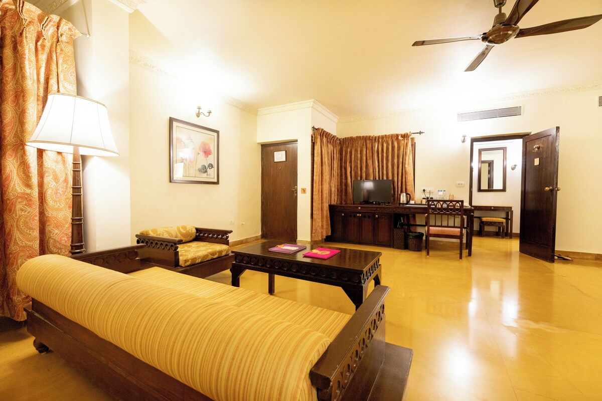 A hotel room with a bed, a desk, a chair, a television, and a ceiling fan.