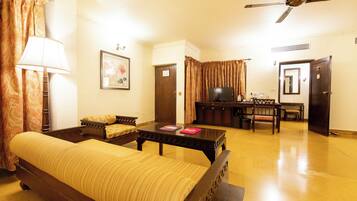 A hotel room with a bed, a desk, a chair, a television, and a ceiling fan.