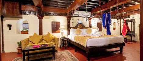 A traditional room with a bed, sofa, and a small table with a rug.