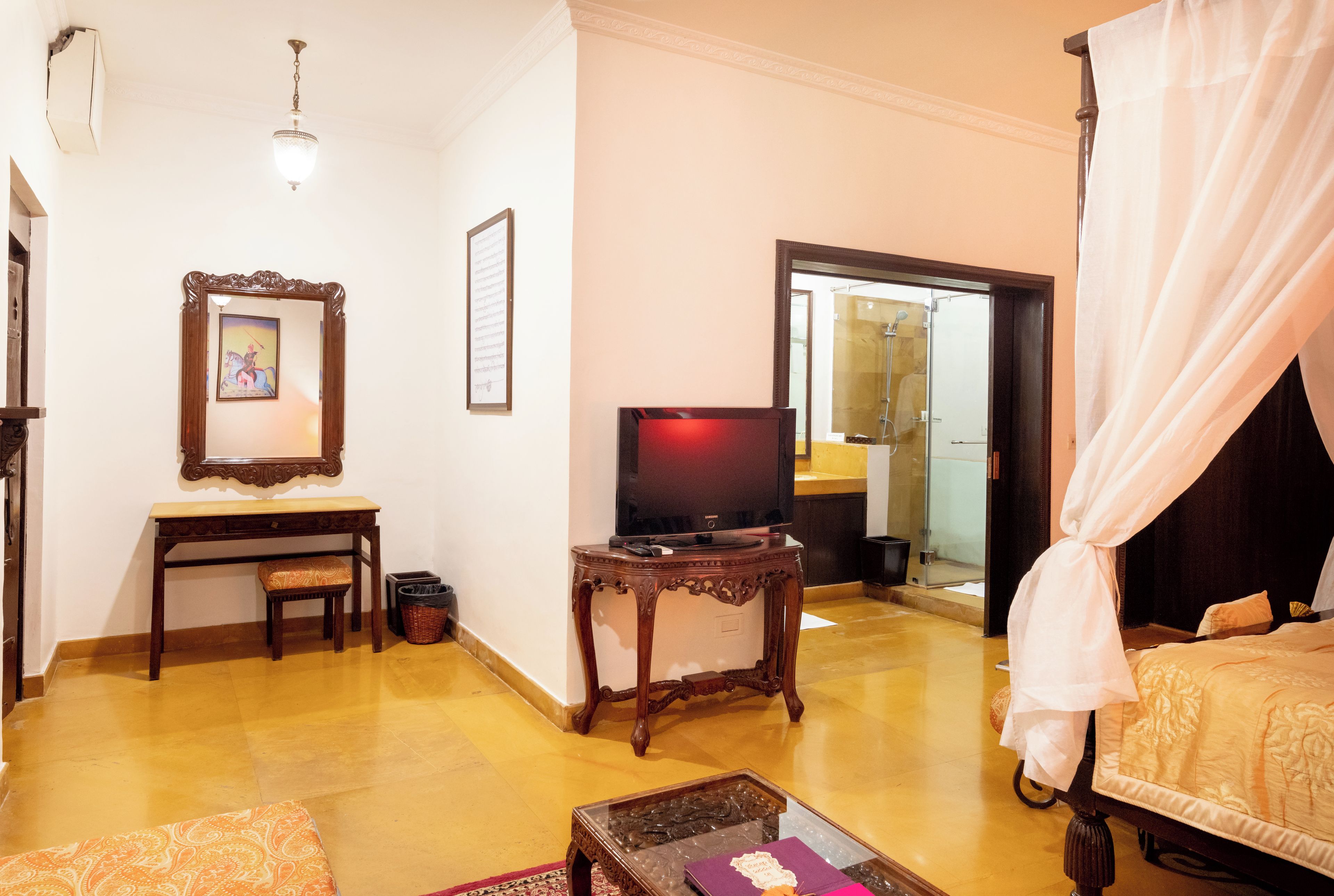 Une chambre d’hôtel comprenant un lit, une télévision, un bureau avec une chaise, une petite table et un miroir.
