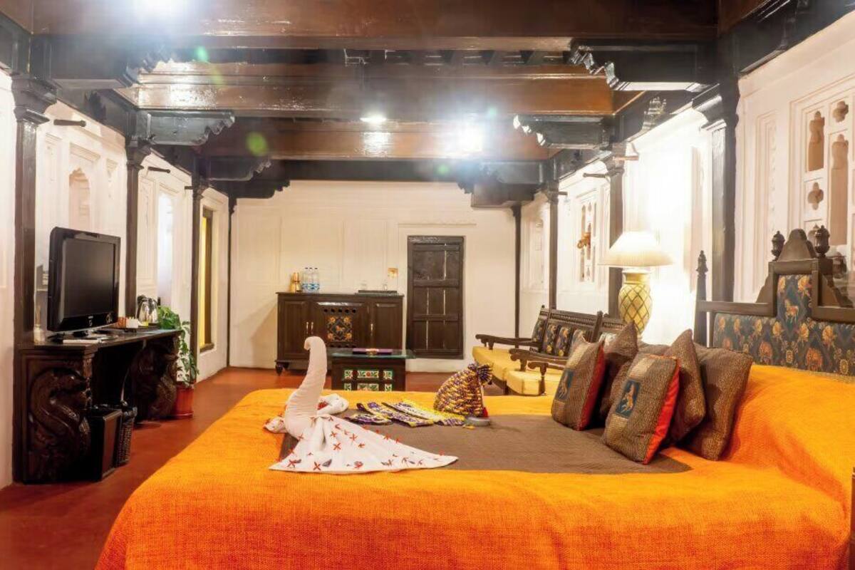A room with a large bed, a television, a desk, and a chair.
