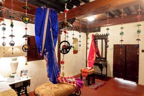 Una habitación tradicional con cama, una silla, una mesa y adornos colgantes.