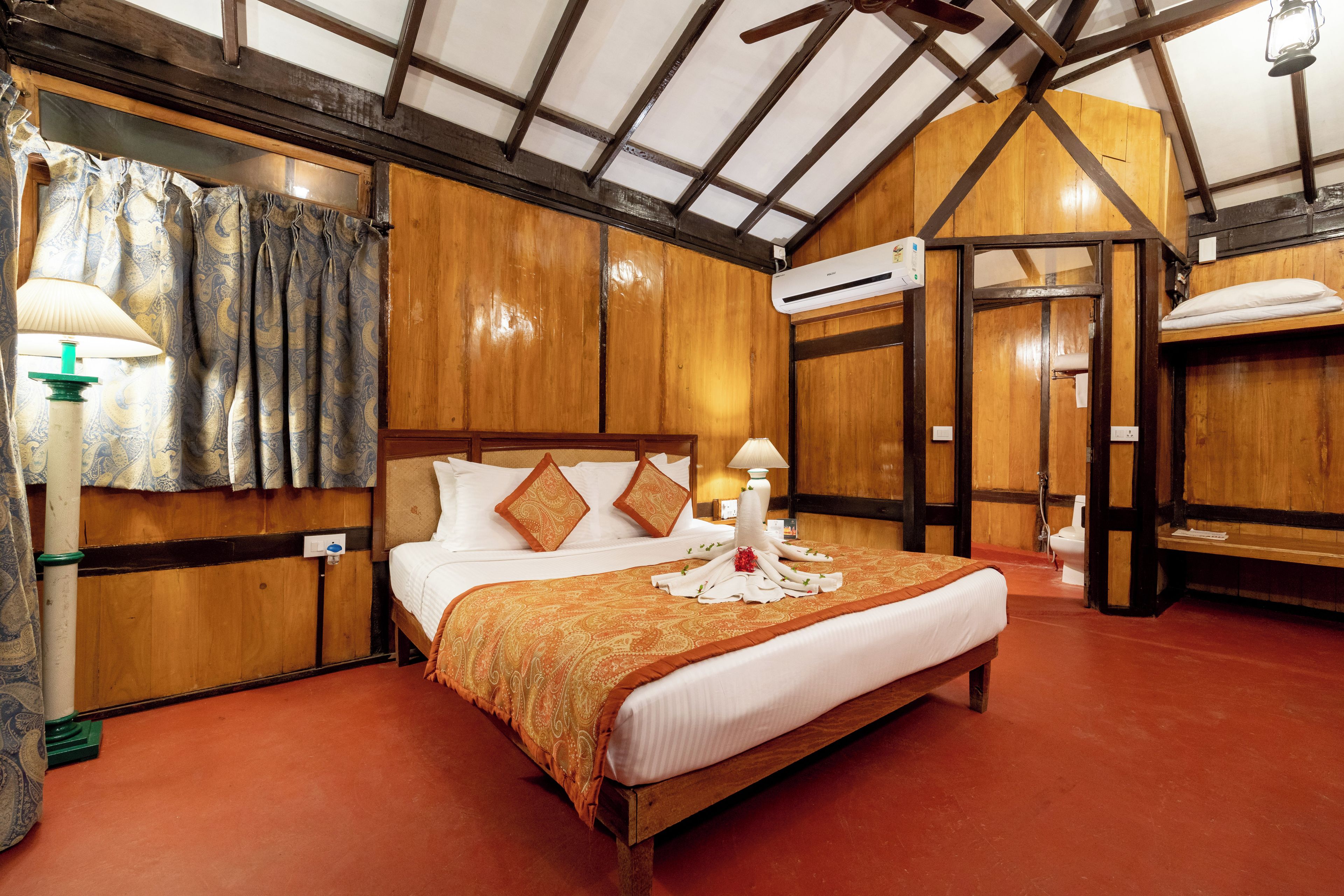Ein Schlafzimmer mit Holzwandverkleidung, einem großen Bett, zwei Nachttischlampen und einer Klimaanlage.