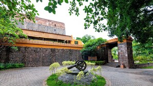 A historic building with a stone wall and a yellow overhang. - Fort Jadhavgadh (Sasvad)