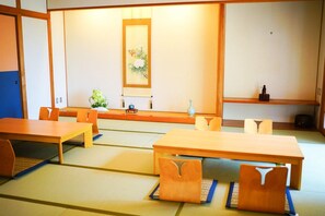 A traditional Japanese tatami room with tatami mats, low tables, and chairs. - Kaze No Mori (Sakai)