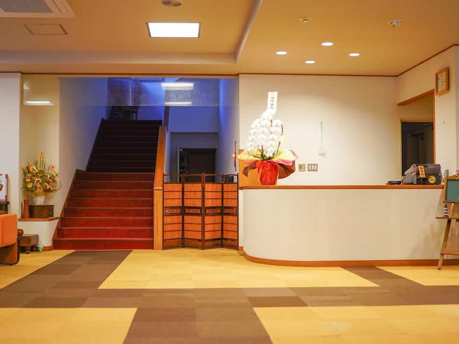 A reception area with a staircase, a reception desk, and a small easel with flowers.