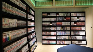 A room with a large bookshelf filled with books, a bed, and a ceiling with green lighting. - Henn Na Hotel Express Nagoya Fushimi Ekimae (Nagoya)