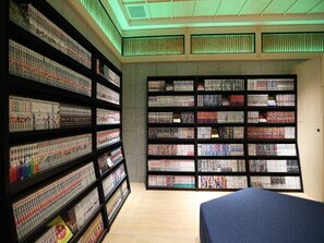 A room with a large bookshelf filled with books, a bed, and a ceiling with green lighting. - Henn Na Hotel Express Nagoya Fushimi Ekimae (Nagoya)