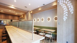 Un interior de restaurante moderno con una larga barra de madera, varias zonas de estar y una pared decorativa con diseños circulares.