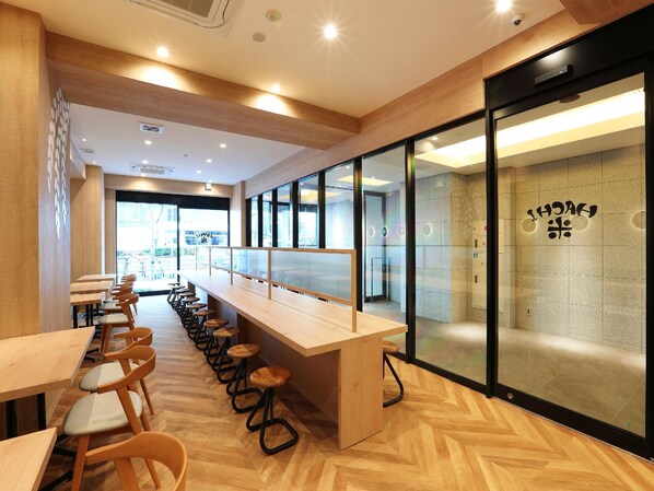 A modern cafe with wooden furniture, a long counter, and large windows. - Henn Na Hotel Express Nagoya Fushimi Ekimae (Nagoya)