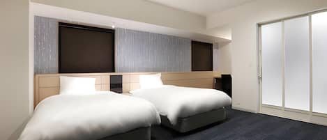 Habitación de hotel con dos camas, un armario y un ventanal grande.