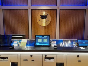 A reception desk with a laptop displaying a digital menu, a gold plaque with Japanese text, and a wooden panel wall. - Henn Na Hotel Express Nagoya Fushimi Ekimae (Nagoya)