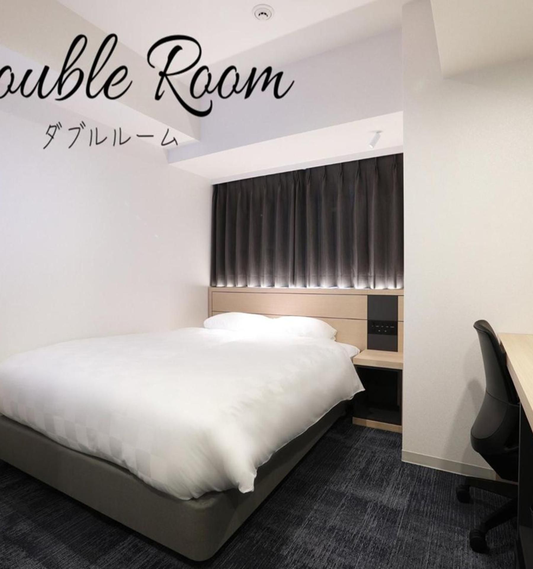 Habitación doble con cama, mesita de noche y escritorio con silla.