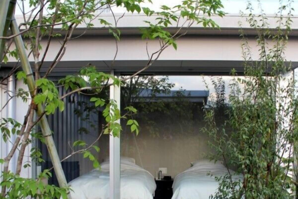 Quarto moderno com duas camas, uma janela grande e vista para o exterior.