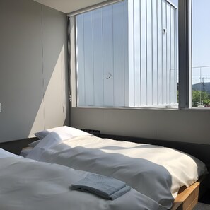 A bedroom with a bed, a window, and a view of the outside. - Arita Huis (Arita)