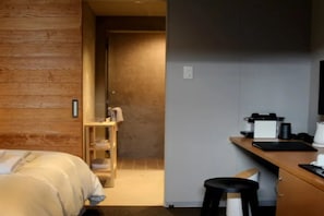 A hotel room with a bed, a desk with a chair, a coffee maker, and a television. - Arita Huis (Arita)