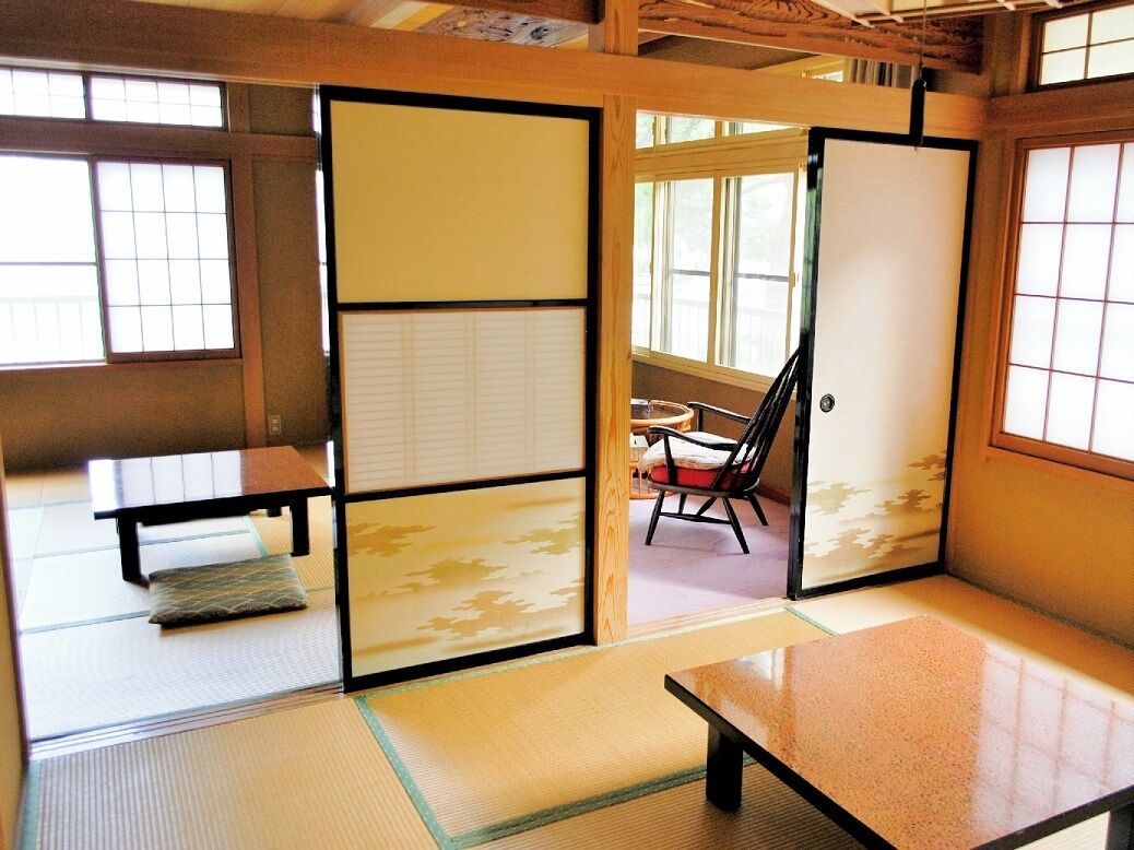 A tatami mat room with sliding doors, a low table, and a chair.