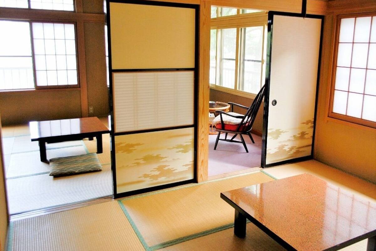 Et traditionelt japansk rum med tatamimåtter, skydedøre, et lavt bord og en stol.