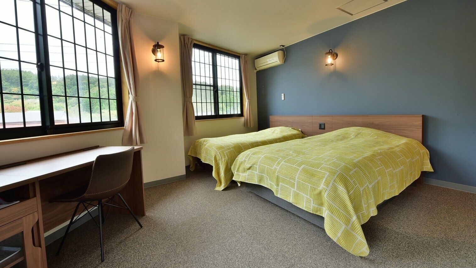 A room with two beds, a desk, and a chair.