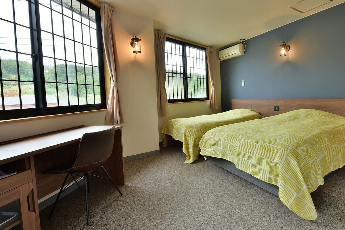 Ein Zimmer mit zwei Betten, einem Schreibtisch und einem Stuhl.