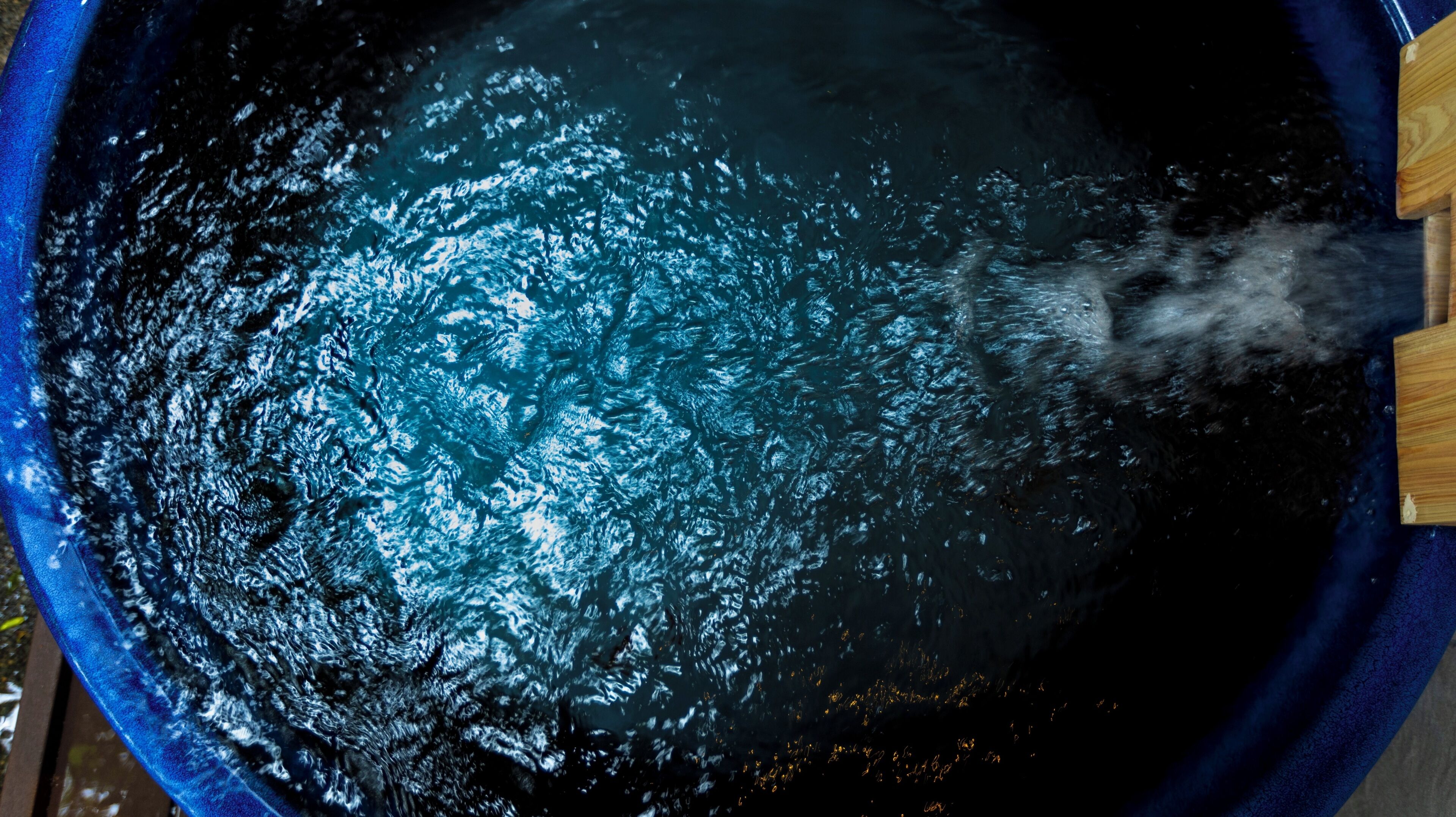Une grande baignoire ronde et bleue dans laquelle on verse de l’eau.