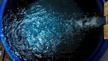 Une grande baignoire ronde et bleue dans laquelle on verse de l’eau.