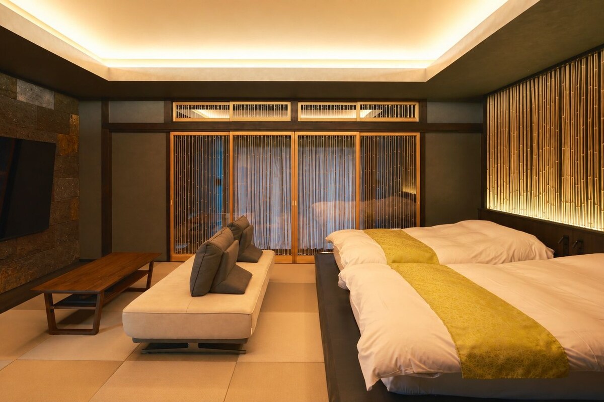 Une chambre moderne avec un canapé, deux lits, une télévision et une grande fenêtre avec des rideaux.