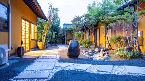 A traditional Japanese garden with a stone pathway, a large stone lantern, and a building with sliding doors. - Tamana Onsen Nakoikan Villa Tamayura (Tamana)