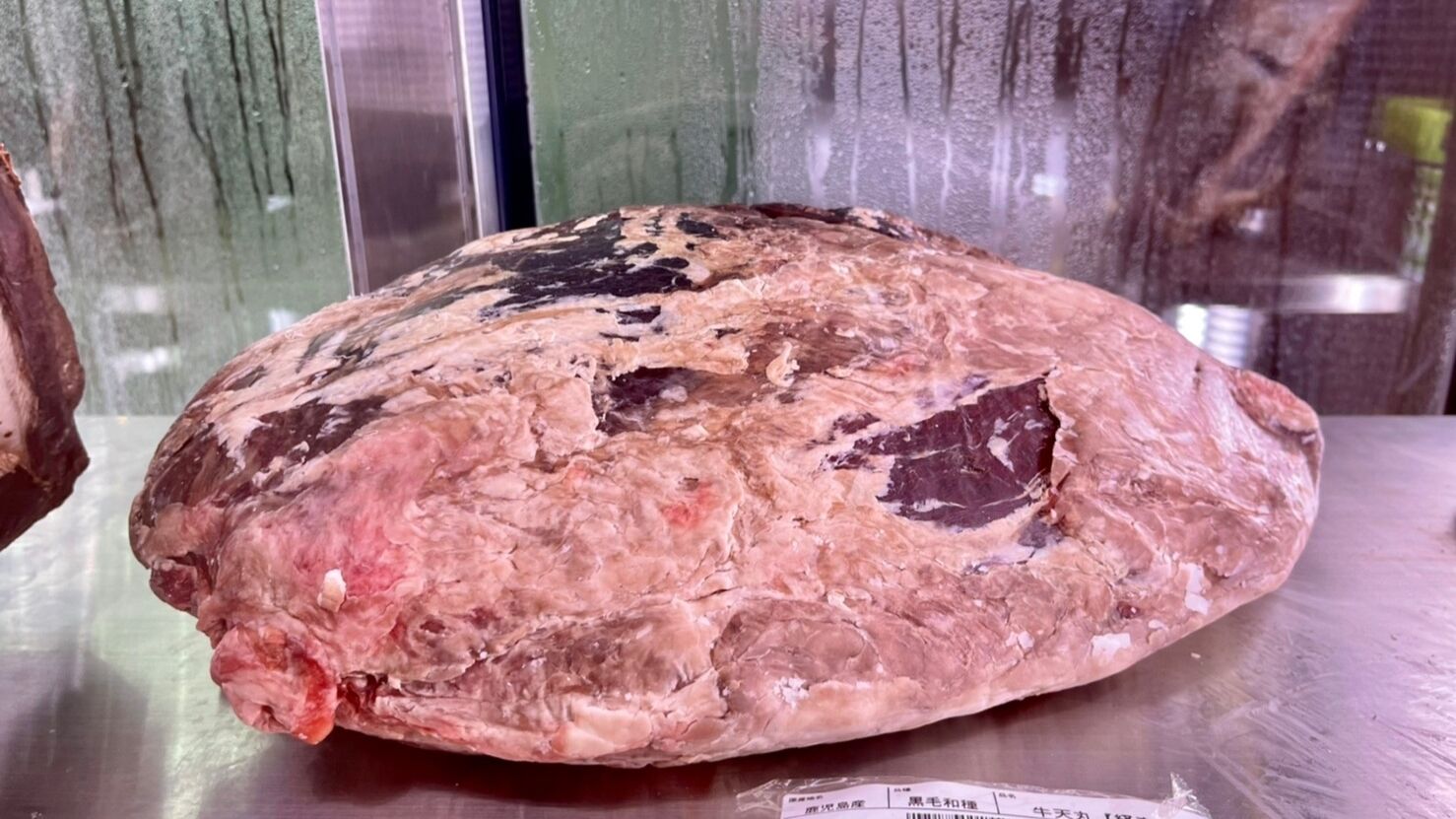 A large, irregularly shaped object with a rough texture, possibly a piece of meat, on a metallic surface.