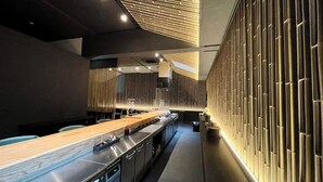 A modern kitchen with a long counter, stainless steel appliances, and a unique bamboo wall design. - Tamana Onsen Nakoikan Villa Tamayura (Tamana)