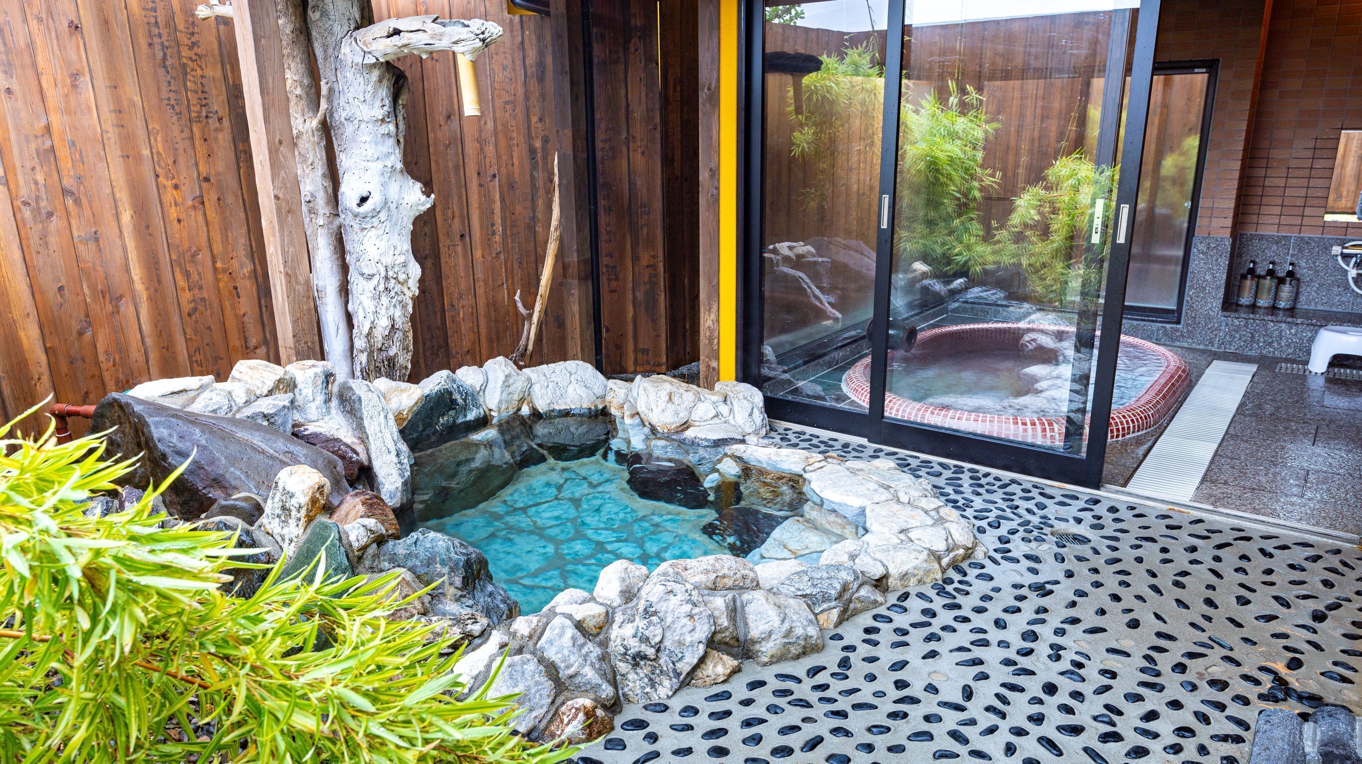 A hot tub surrounded by rocks and a wooden fence.