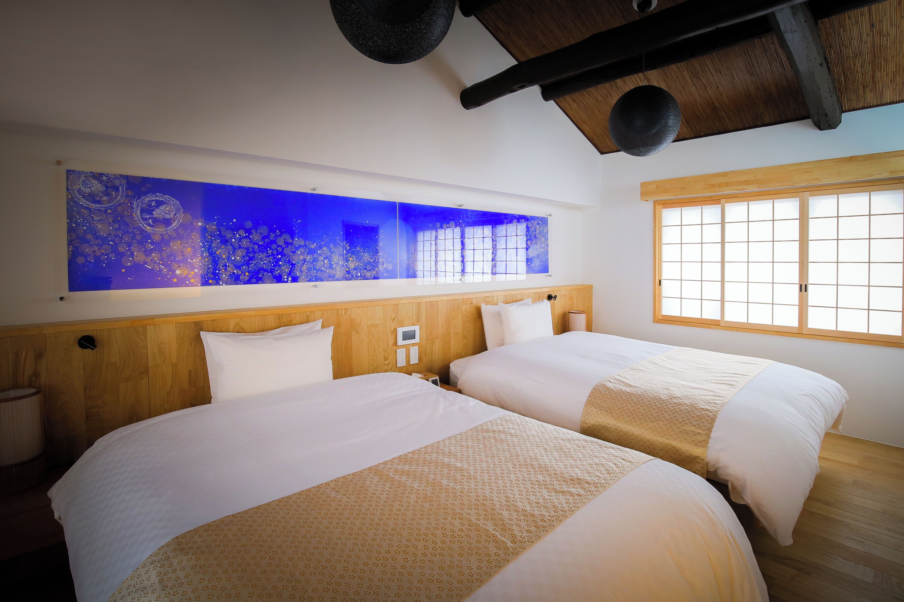 Ein Hotelzimmer mit zwei Betten, einem großen Fenster und einem an der Wand befestigten Aquarium.