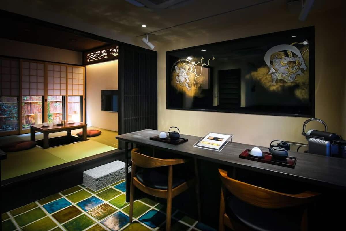Ein traditioneller japanischer Raum mit Tatami-Böden, einem niedrigen Tisch mit Teeservice und einem großen Spiegel mit Kunstwerken.