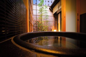 A traditional Japanese-style interior with a stone water feature, wooden sliding doors, and a bamboo plant.