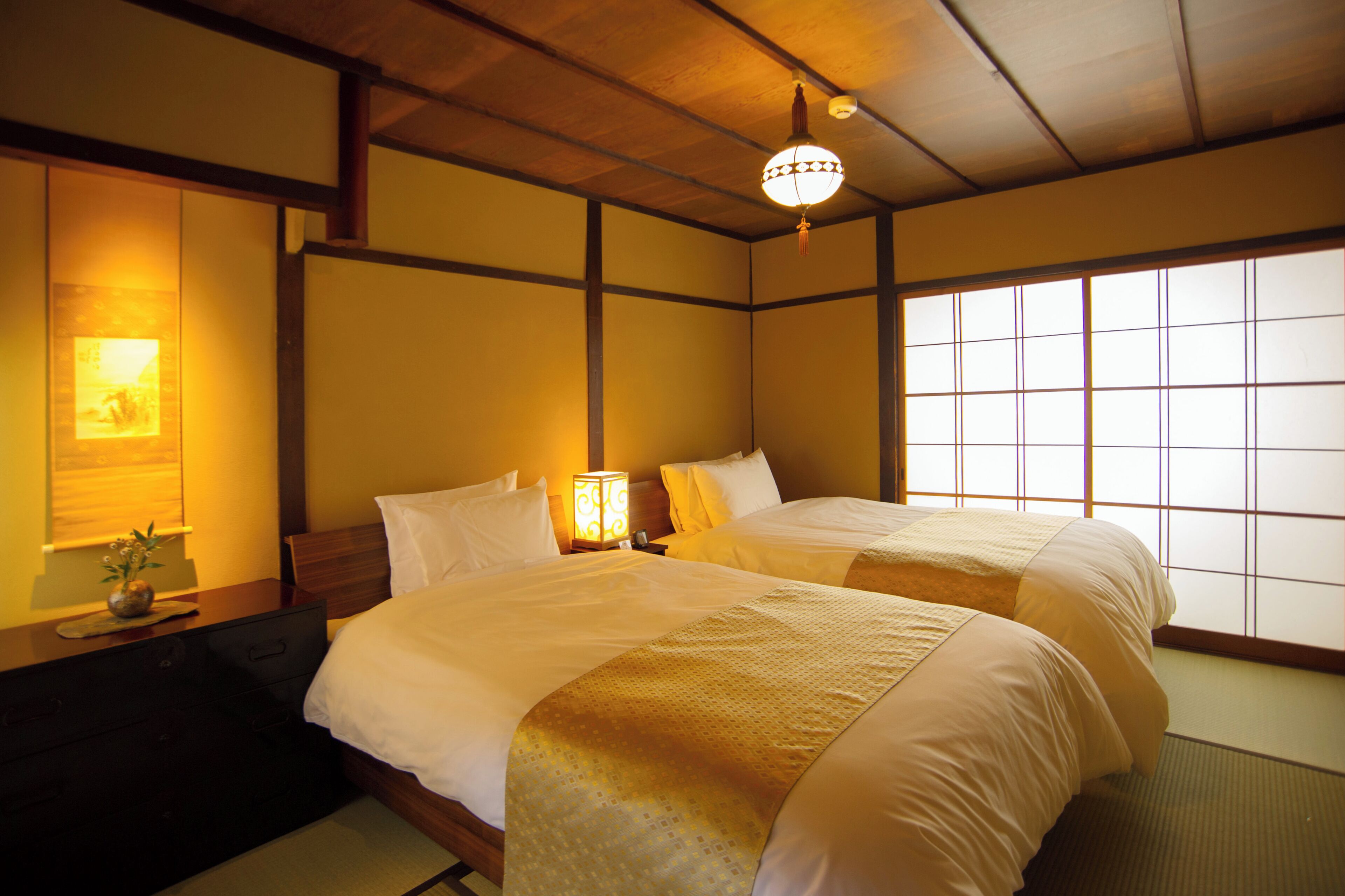 Ein traditionell eingerichtetes Hotelzimmer im japanischen Stil mit Tatami-Böden, einem Shoji-Bildschirm und einem Futon-Bett.