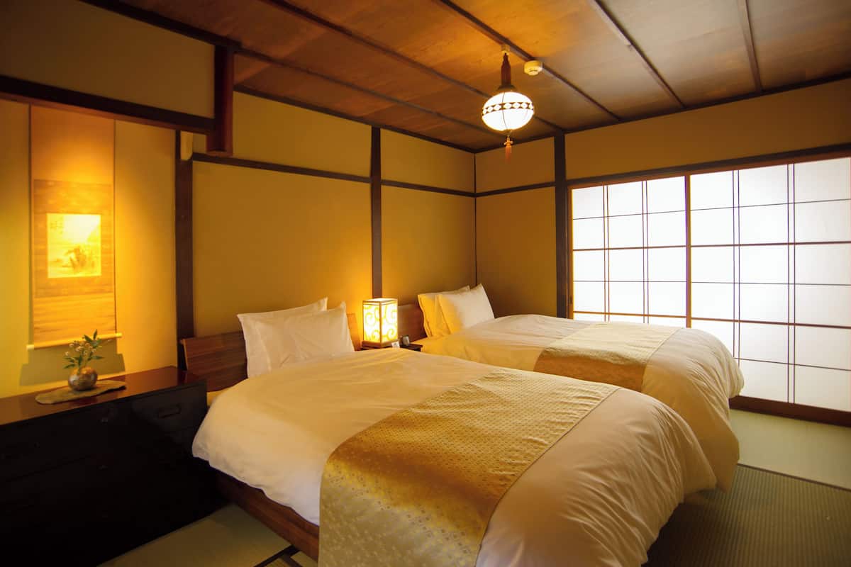 Ein traditionell eingerichtetes Hotelzimmer im japanischen Stil mit Tatami-Böden, einem Shoji-Bildschirm und einem Futon-Bett.