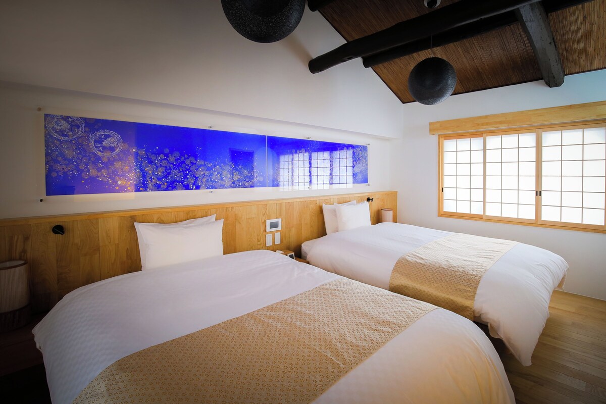 Habitación de hotel con dos camas, un ventanal grande y un acuario instalado en la pared.