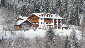 A large wooden chalet with multiple balconies, surrounded by snow-covered trees. - Gasthof Gra Benhof (Vienna)