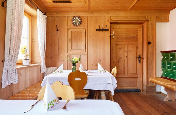 Una habitación de madera con dos mesas dispuestas para comer, un reloj en la pared y un banco.