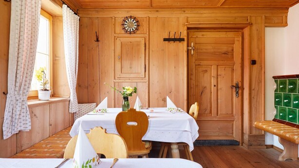 A wooden room with two tables set for dining, a clock on the wall, and a bench. - Gasthof Gra Benhof (Vienna)