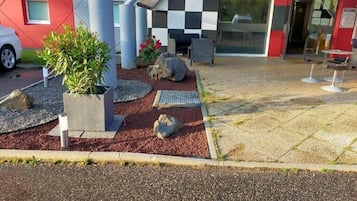 A modern building with a checkered facade, outdoor seating, and a gravel pathway.