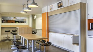 A modern kitchen with a wooden countertop, bar stools, and pendant lighting. - Hotel Lemon (Coudes)