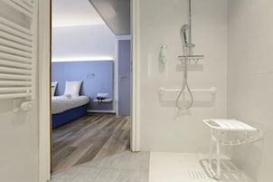 Un baño moderno con ducha, inodoro y una mesita de noche con una botella.