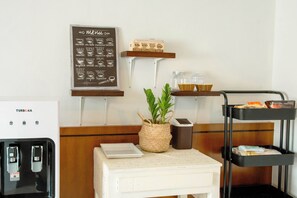 A coffee station with a menu board, a coffee machine, a plant, and a trash bin. - Alley & Pier (Bangkok)