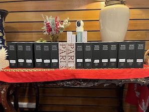 A display of black dictionaries with white labels on a wooden table, a vase with red berries, and a surveillance camera. - Alley & Pier (Bangkok)