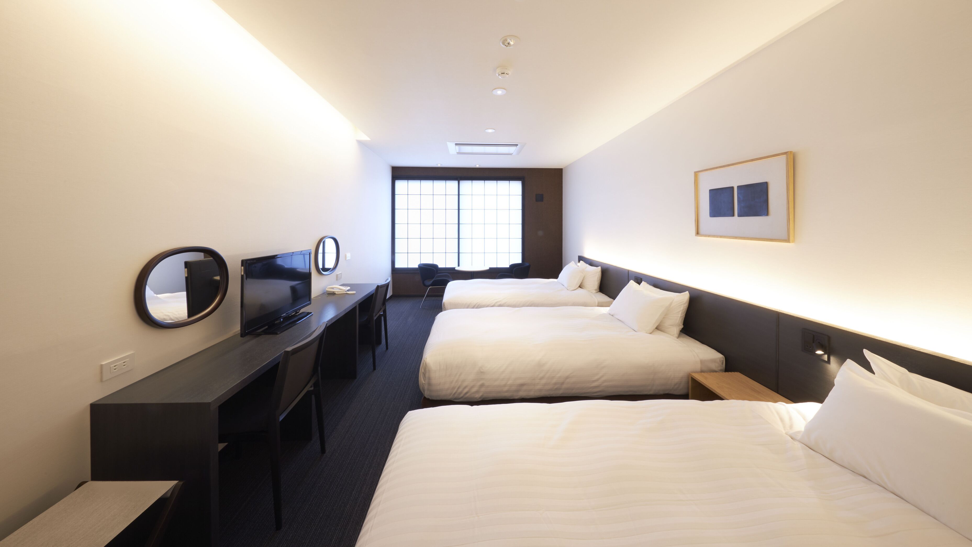 Ein Hotelzimmer mit zwei Betten, einem Schreibtisch mit Fernseher, einem Spiegel und einem Fenster.