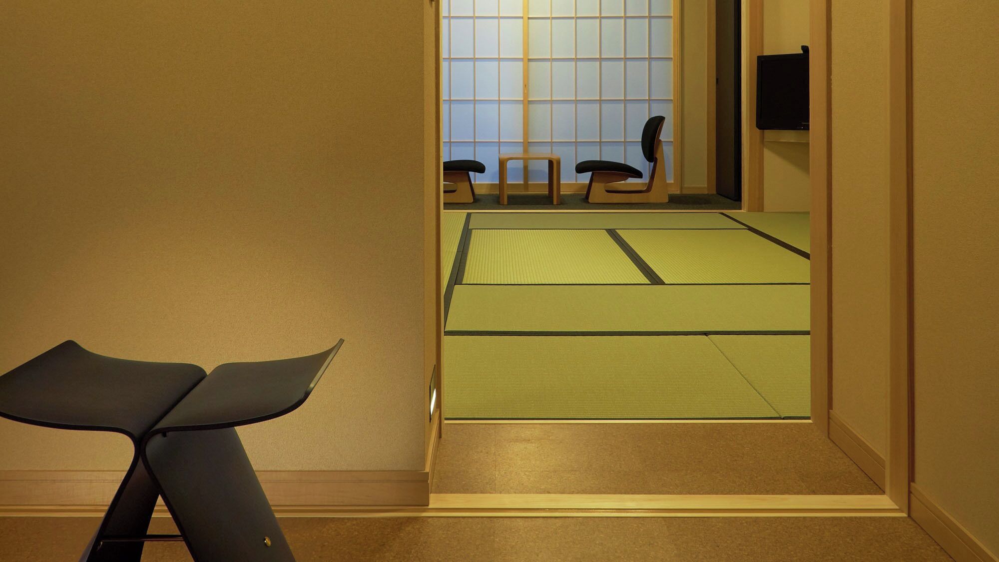 A room with tatami mats, a low table, and a sliding door leading to another space.