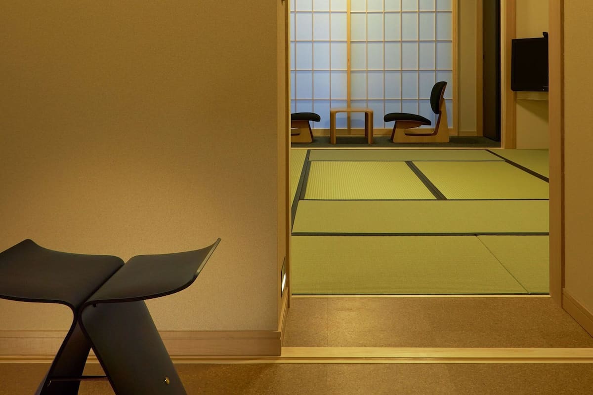 Une pièce avec des tatamis, une table basse et une porte coulissante donnant sur une autre pièce.