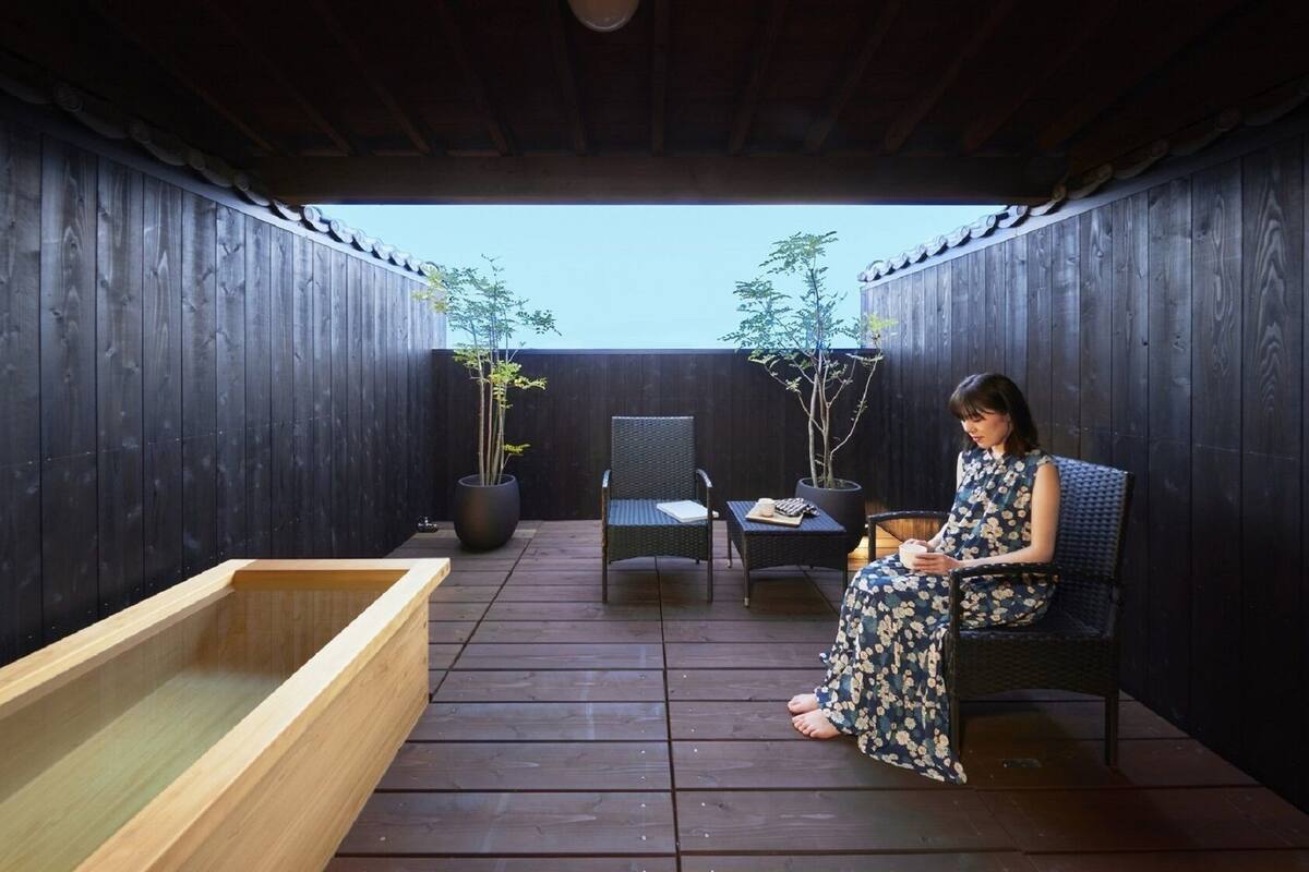 Une terrasse en bois avec un jacuzzi, des chaises et des plantes en pot.